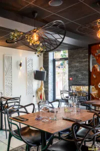 Salle de restaurant moderne avec tables dressées, chaises noires design.