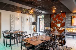 Salle de restaurant moderne avec tables dressées, chaises noires design.