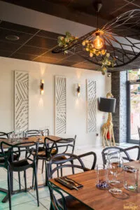 Salle de restaurant moderne avec tables dressées, chaises noires design.