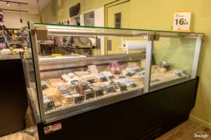 Comptoir réfrigéré vitré présentant divers morceaux de fromage