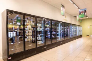 Vitrines réfrigérées vitrées pleines de produits frais sous l’enseigne « L’Espace frais » dans un rayon de magasin.
