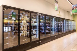 Vitrines réfrigérées vitrées pleines de produits frais sous l’enseigne « L’Espace frais » dans un rayon de magasin.