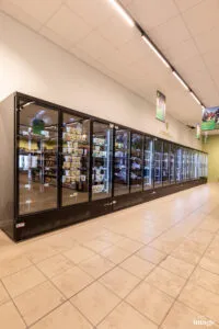 Vitrines réfrigérées vitrées pleines de produits frais sous l’enseigne « L’Espace frais » dans un rayon de magasin.