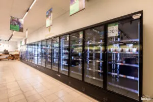 Vitrines réfrigérées vitrées pleines de produits frais sous l’enseigne « L’Espace frais » dans un rayon de magasin.